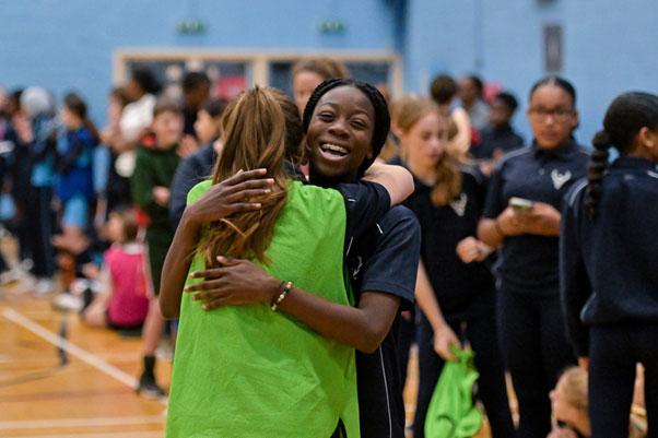 black girl hugs white girl at sportshall athletics