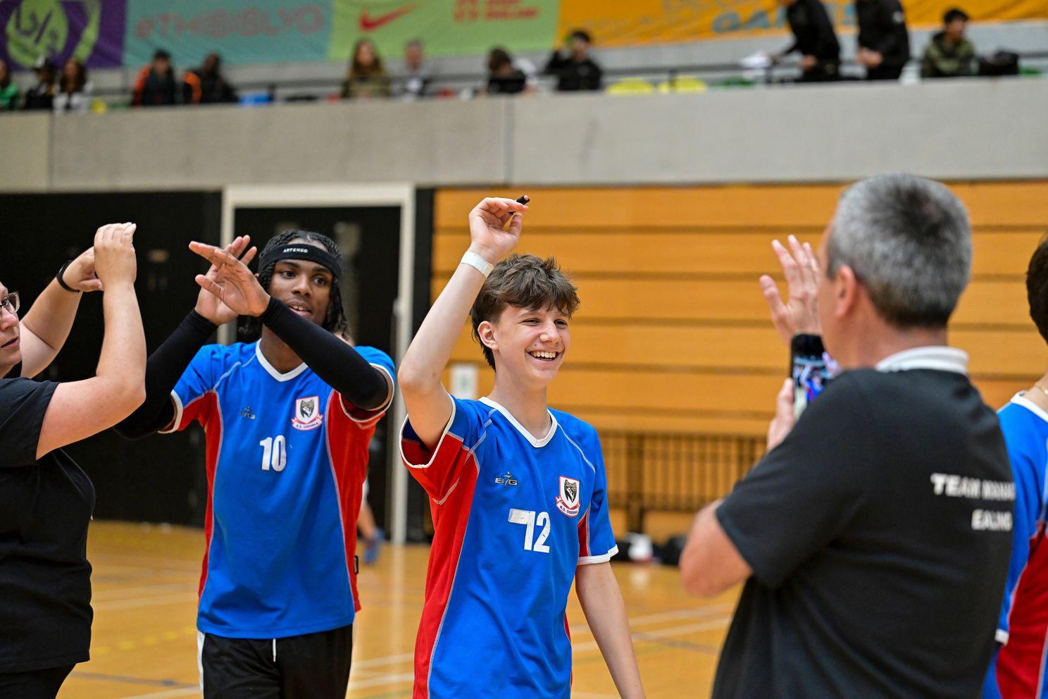 1 black boy and 1 white boy high fives coach